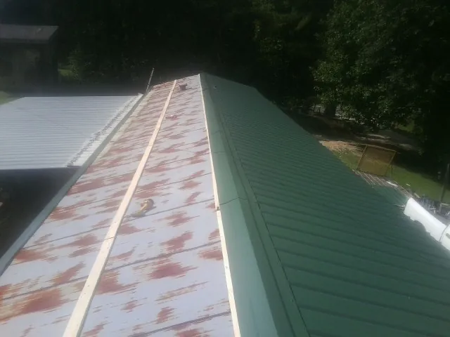 Old rusted panels beside newly installed green metal roofing — Wind Damage Roof Repair by Roofing Brothers in Weaverville