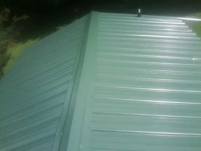 New green metal panels meeting at the ridge of a roof — Flat Roof Repair work by our crew in Weaverville